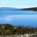 A rocky coastline along a large body of water with hills in the distance